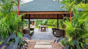 A covered outdoor area with a table and chairs, surrounded by lush tropical plants. - Villa Raeya (Krabi)