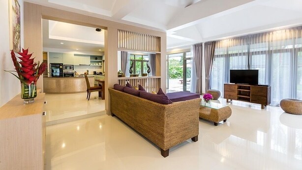 A modern living room with a wicker sofa, a flat-screen TV, and a glass coffee table. - Villa Raeya (Krabi)