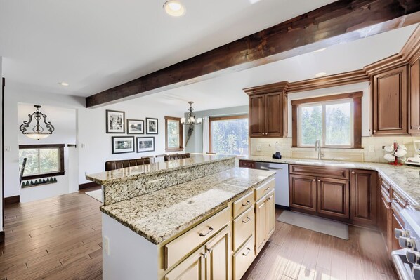 A spacious kitchen with granite countertops, wooden cabinets, and a large island.