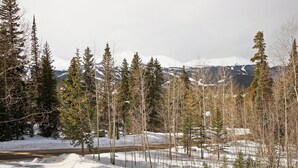 Schneebedeckte Landschaft mit einer Straße, Bäumen und Bergen im Hintergrund.