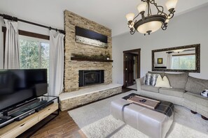 Una sala de estar con chimenea de piedra, un televisor de pantalla plana, un sofá y una mesa de centro.