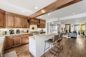 Una cocina amplia con armarios de madera, encimera de granito y una isla central con taburetes de bar.