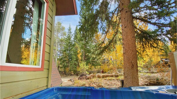 Un bain à remous situé dans un espace boisé, avec une maison en bois en arrière-plan.