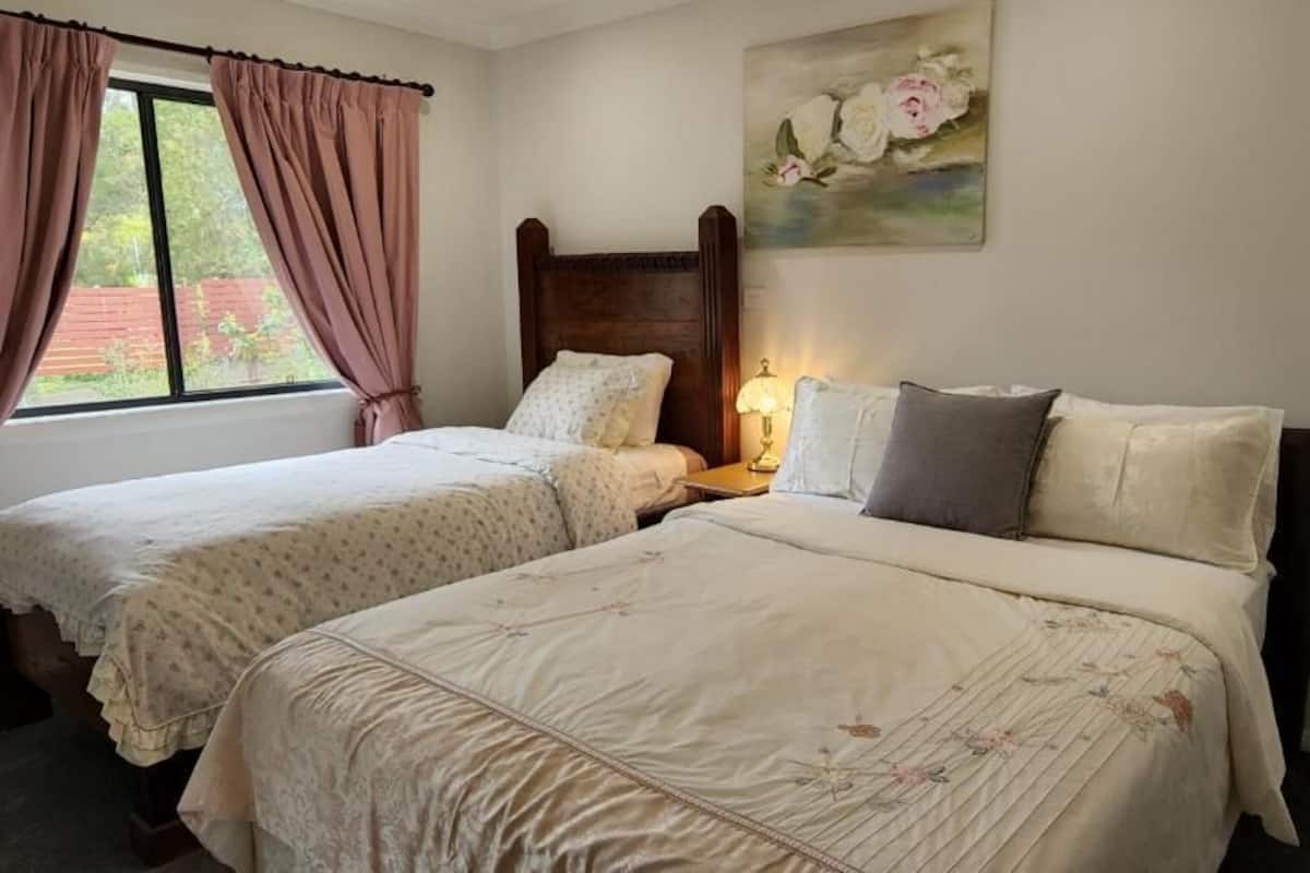 Ein Schlafzimmer mit zwei Einzelbetten, einem Holzkopfstück, einem Nachttisch mit Lampe und einem Bild an der Wand.