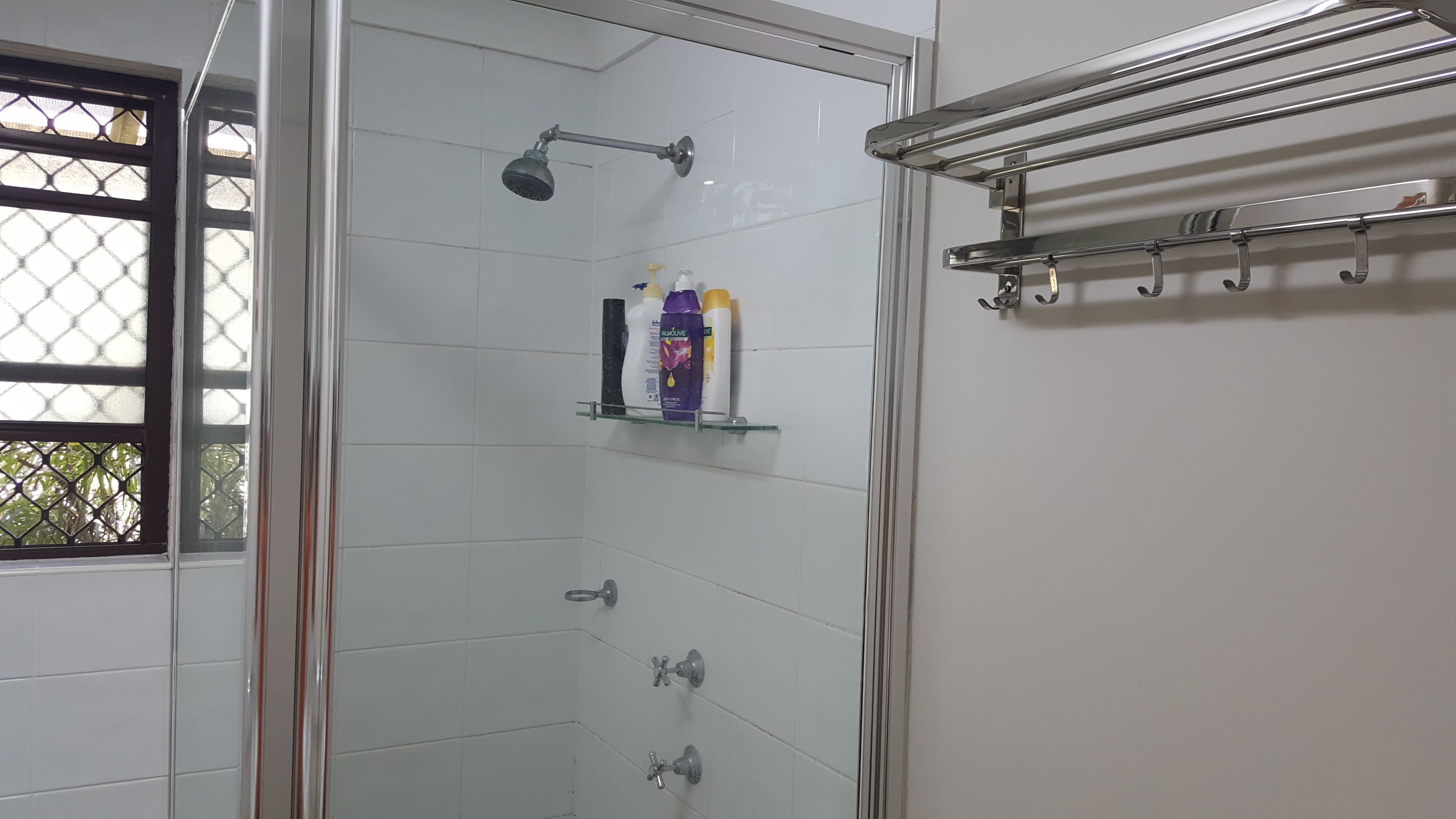Ducha con paredes de vidrio, cabezal de ducha manual y varios grifos.