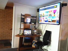 Un espacio de trabajo en casa con un escritorio, estanterías y un televisor mostrando un sitio web con temática de globos.