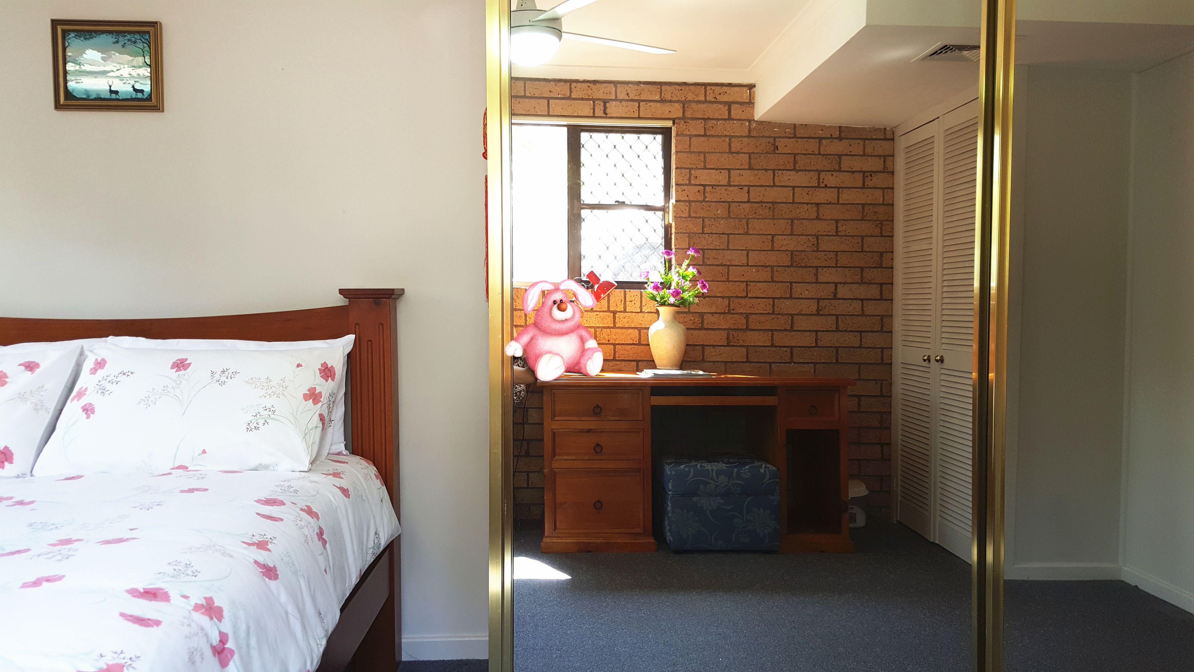 A bedroom with a bed, a desk, a chair, a window, and a wardrobe.