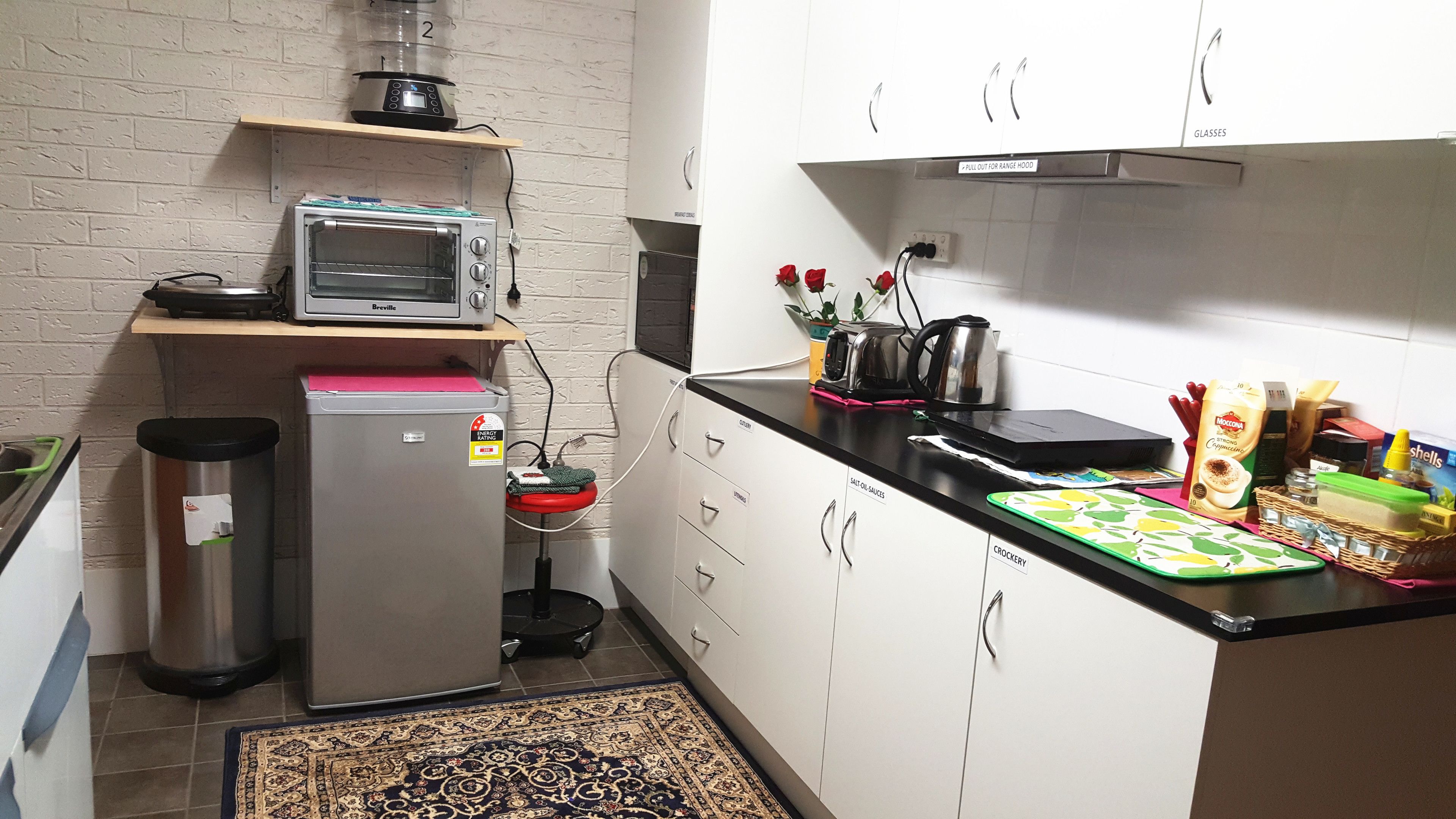 Eine kompakte Küche mit einem Breville-Toasterofen, einem Edelstahl-Kühlschrank und einer Kaffeemaschine.