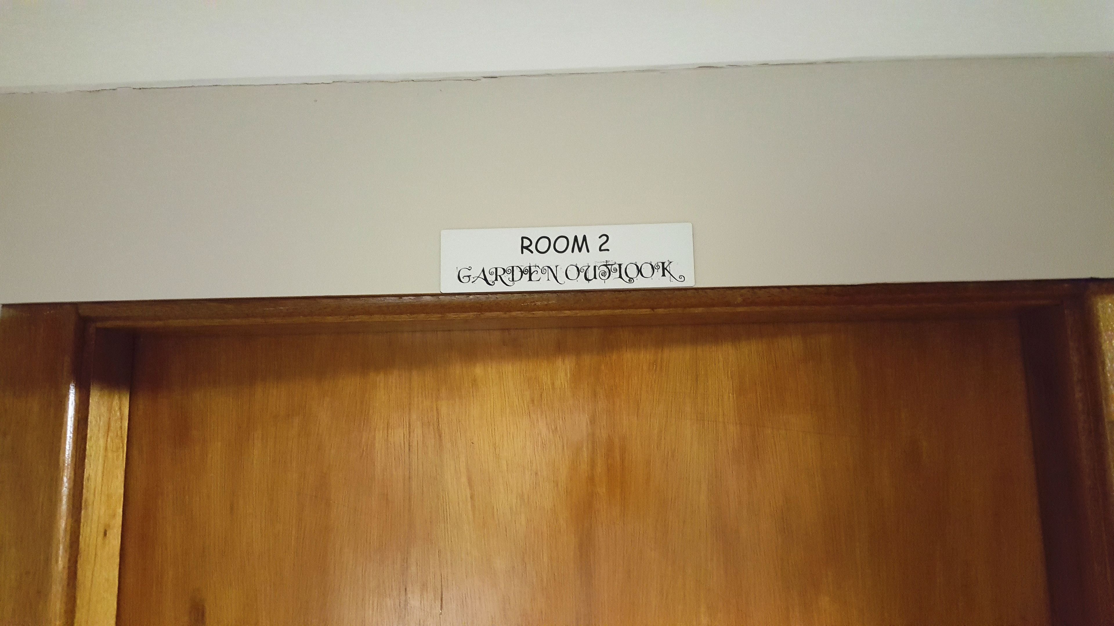 Una puerta de madera con un letrero encima que dice "ROOM 2 GARDEN OUTLOOK".