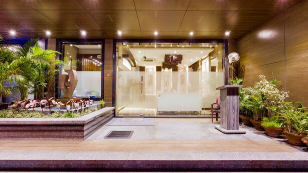 Entrada d'hotel moderna amb façana de vidre, una recepció i diversos vasos amb plantes.