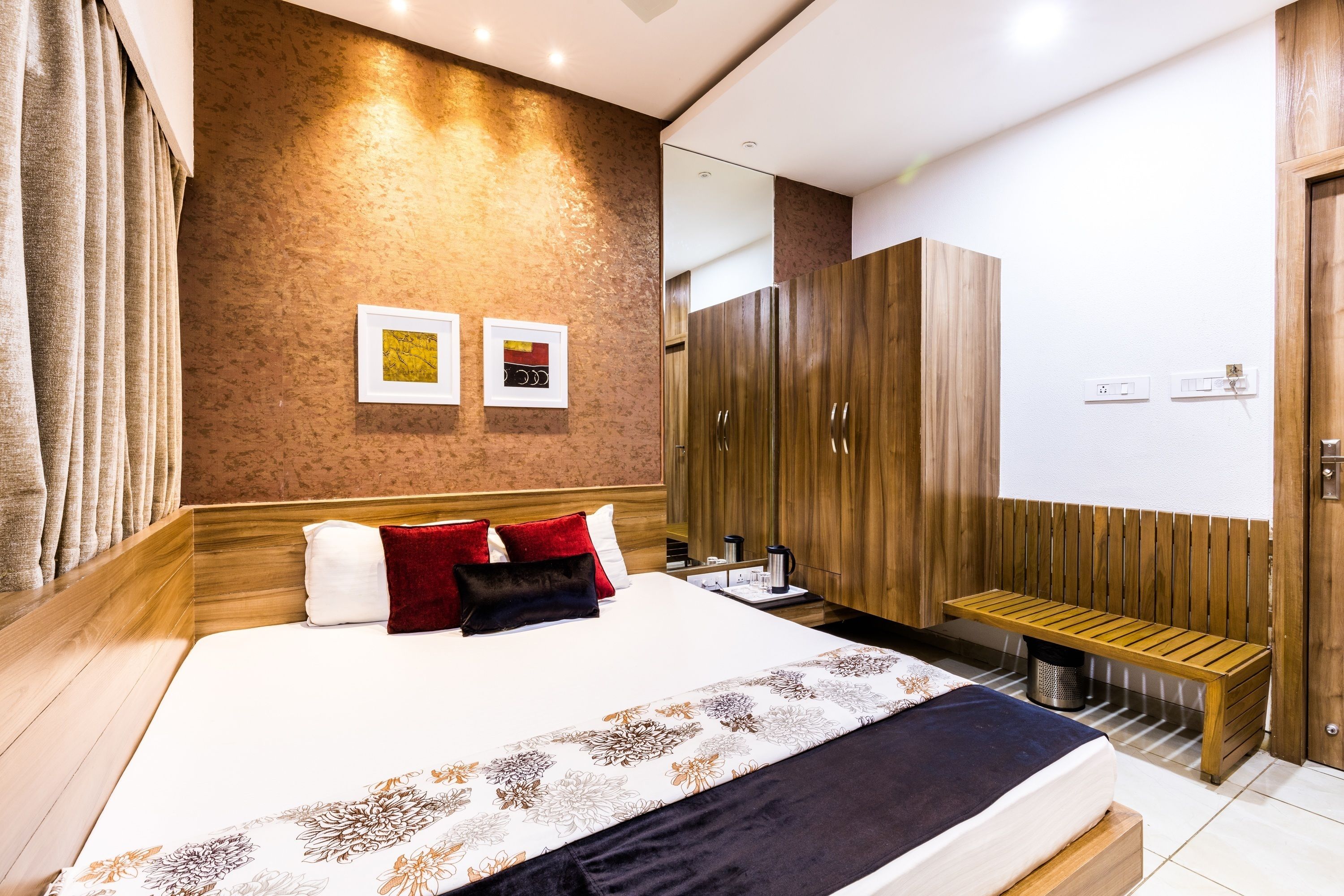 Una habitación de hotel moderna con una cama grande, un armario de madera y un banco.