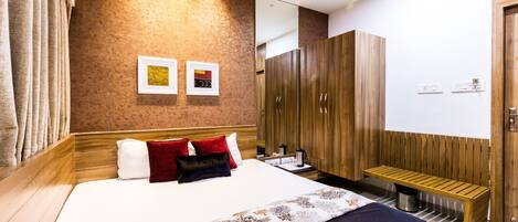 Una habitación de hotel moderna con una cama grande, un armario de madera y un banco.