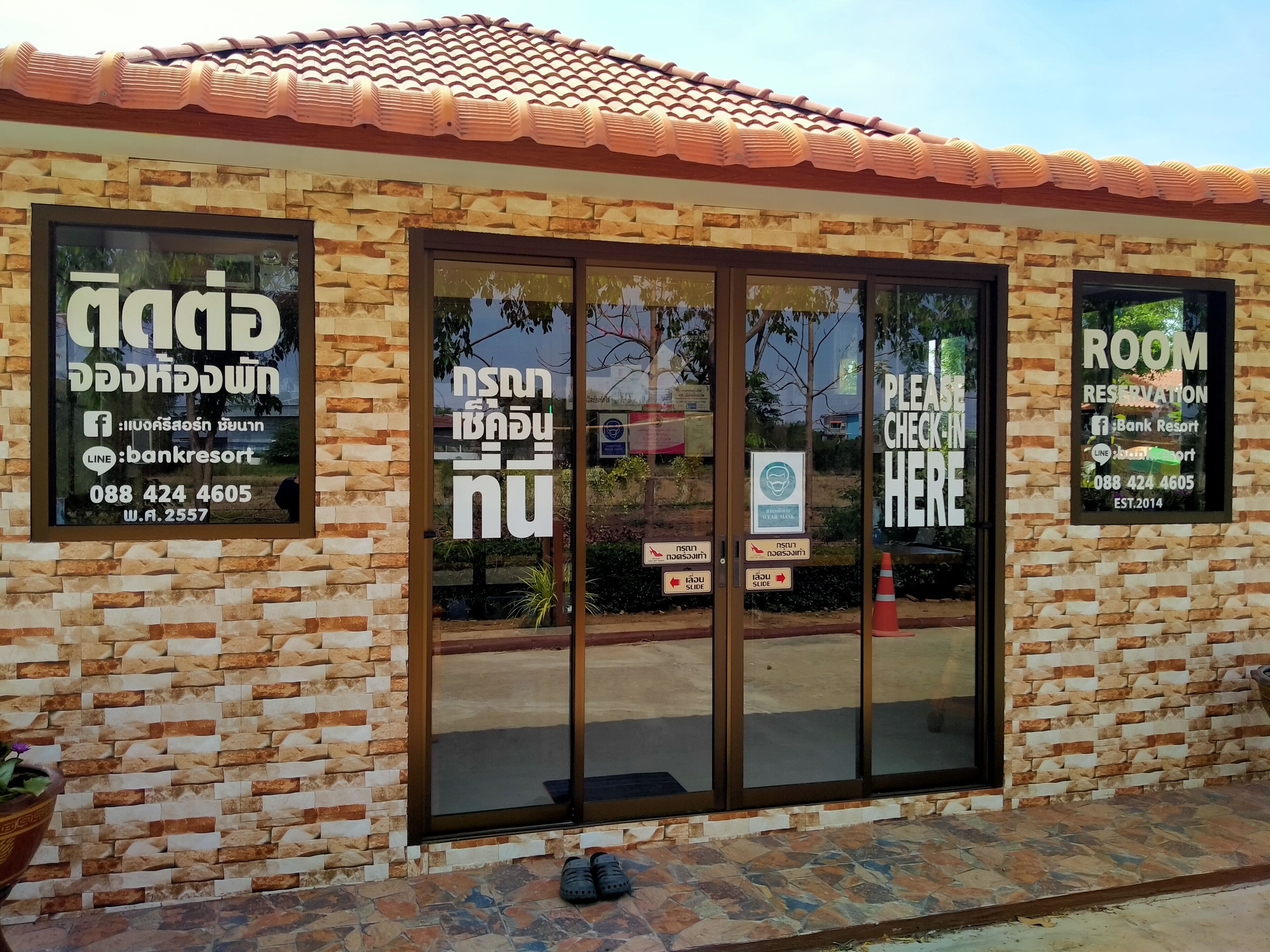 A building with a stone facade, large glass doors, and multiple signs including one for room reservations.
