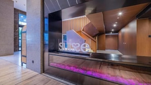 Eine moderne Hotellobby mit einer Glaswand, auf der das Wort "suise" zu sehen ist, und Blick ins Innere.