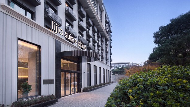 Ein modernes Hotel mit einer markanten Eingangshalle, großen Fenstern und einer gepflegten Fassade.