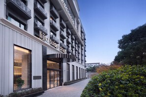Ein modernes Hotel mit einer markanten Eingangshalle, großen Fenstern und einer gepflegten Fassade.
