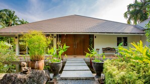 A house with a tiled roof, a wooden door, and a stone pathway leading to the entrance. - Villa Pimmada (Krabi)