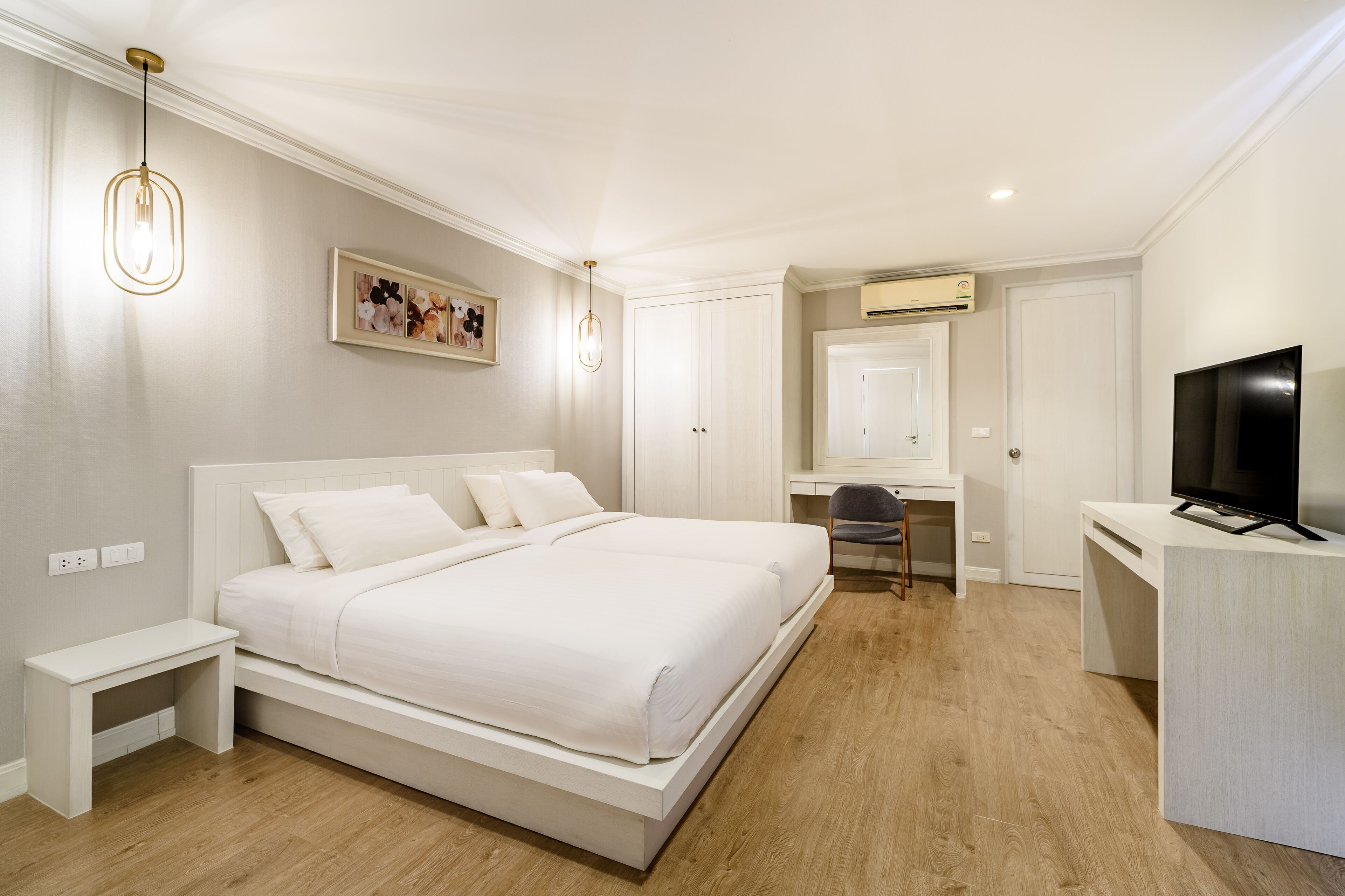 A bedroom with a large bed, a desk, a chair, and a television.
