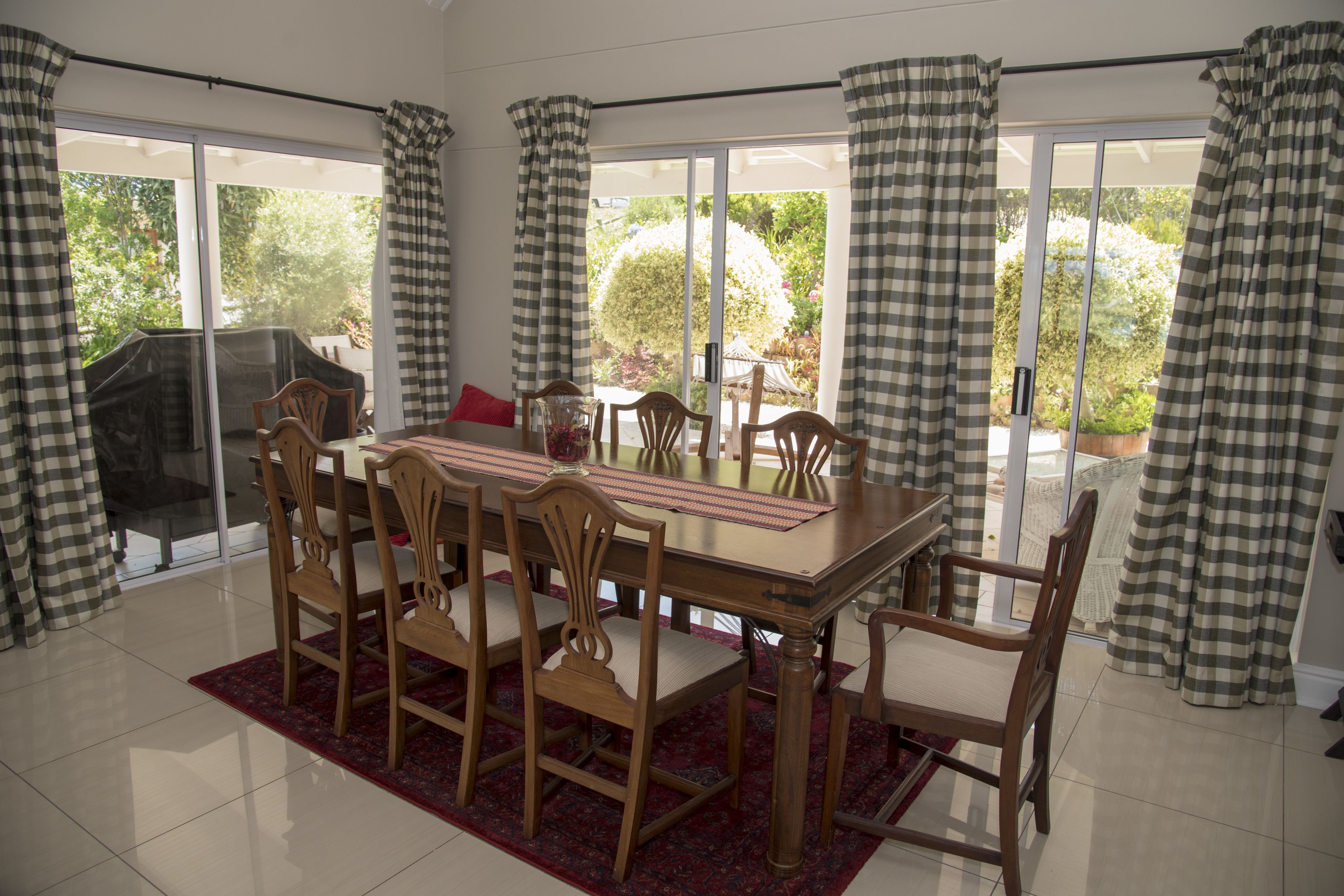 A dining area with a large table, six chairs, and a red rug.