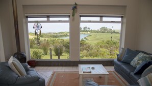 A living room with a large window, a sofa, a coffee table, and a dreamcatcher. - 20 Dunnage (Knysna)