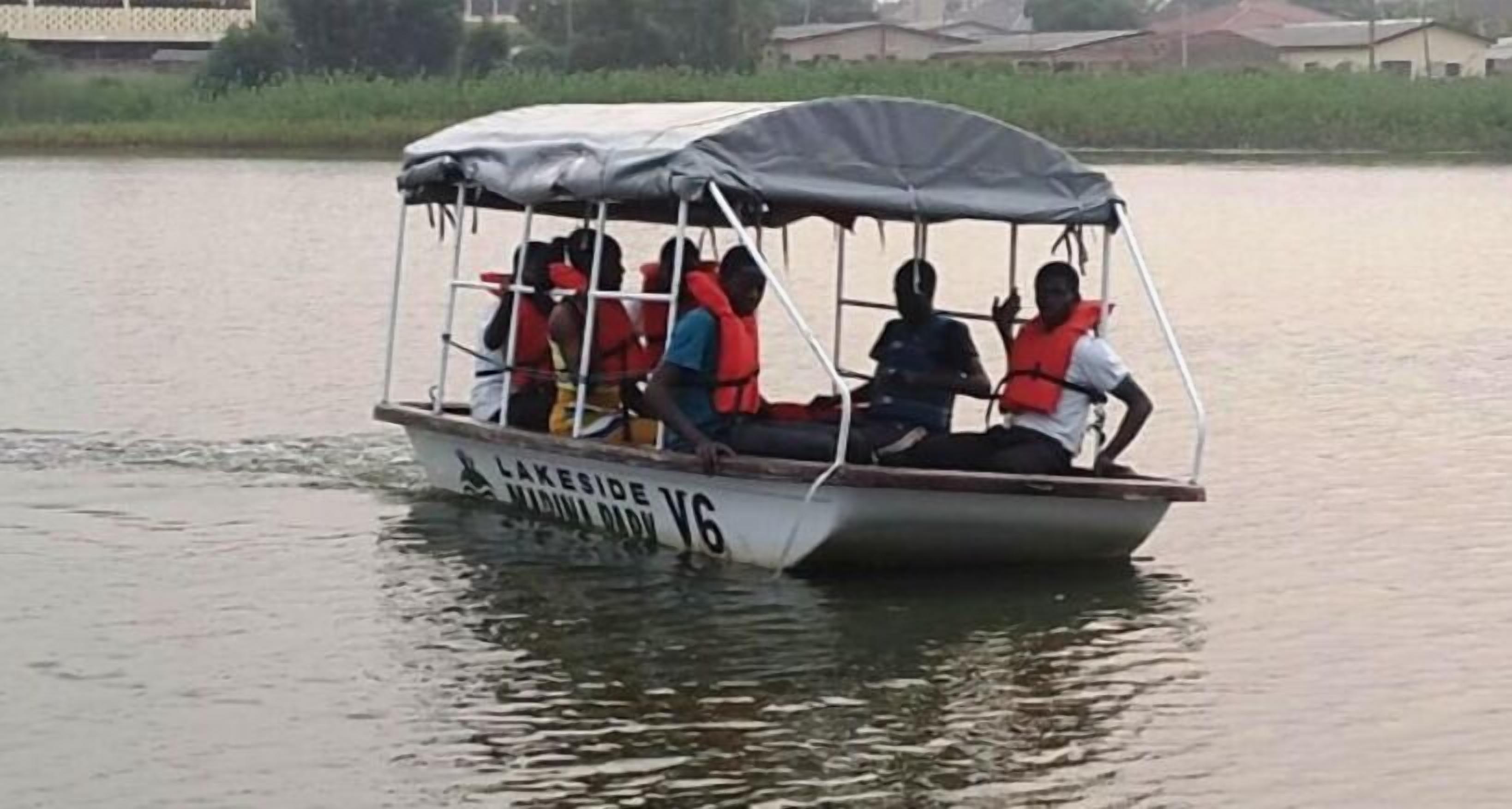 Un bateau doté d’un auvent et transportant des passagers qui portent des gilets de sauvetage, naviguant sur une étendue d’eau calme.