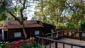 A wooden cabin with a balcony, surrounded by lush greenery and potted plants. - Kinneret Lodging (Tiberias)