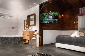 A modern bathroom with a stone-tiled bathtub, wooden vanity, and a large mirror.