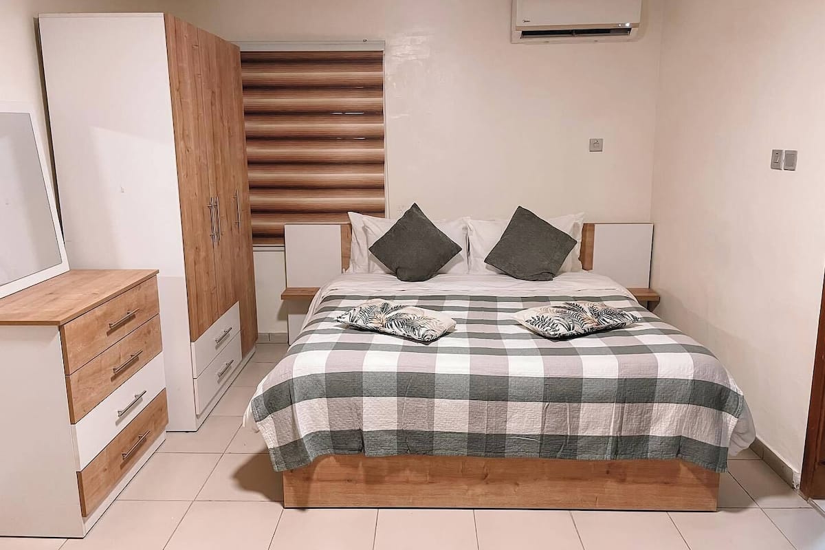 Une chambre à coucher comprenant un lit, une armoire, un bureau et un appareil de climatisation.