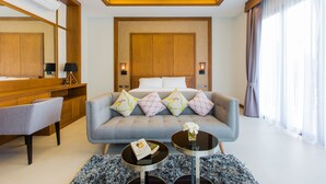 Una habitación de hotel con cama, sofá, mesa de centro, escritorio y un espejo grande.