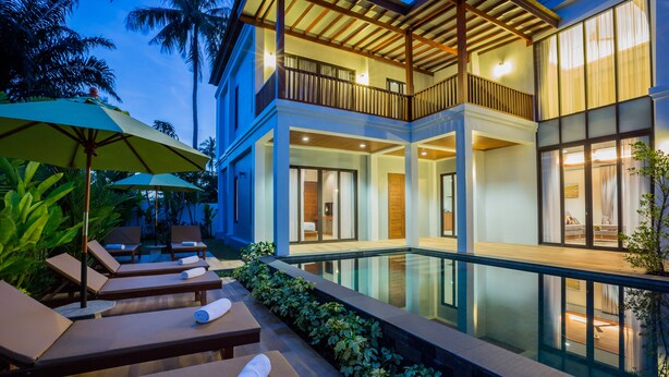 Un resort moderno con piscina, sillones de descanso y un espacio exterior cubierto.