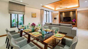 Un área de comedor moderna con una mesa de vidrio, sillas tapizadas de color gris y un sofá.