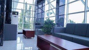 Um interior moderno com uma janela grande, um sofá cinza, uma mesa de madeira e um banco vermelho.