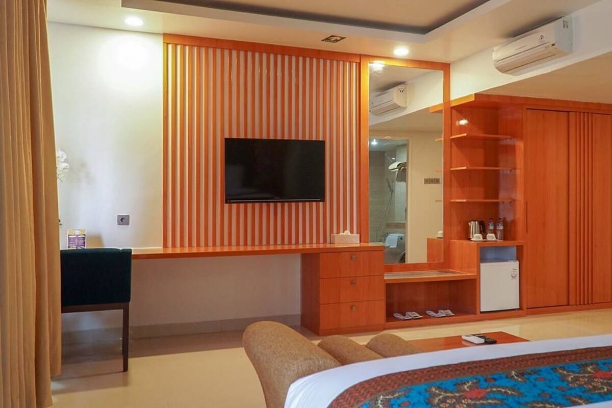 Un dormitorio moderno con cama, escritorio, televisor y armario.