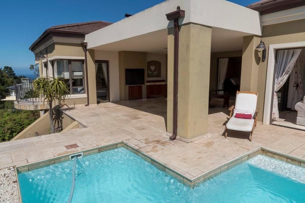 Un área junto a la piscina con tumbonas y un porche cubierto.