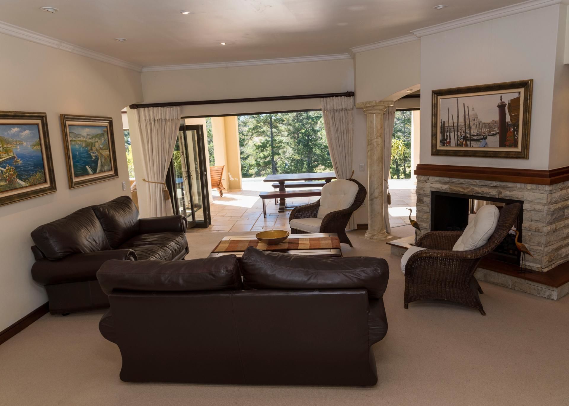 A spacious living room with leather sofas, a fireplace, and a dining area with a table and chairs.