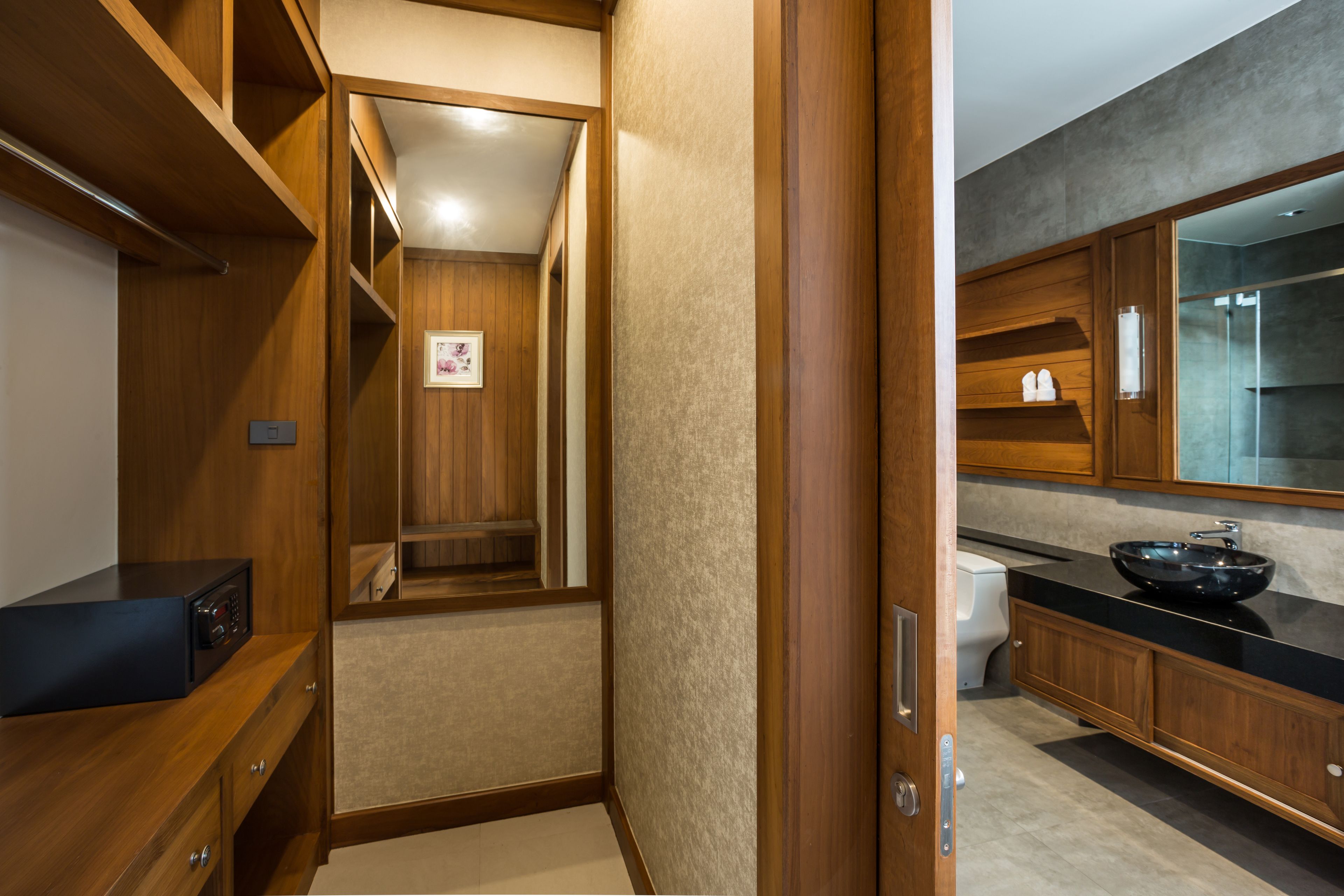 A modern bathroom with wooden cabinetry, a black countertop, and a glass shower enclosure.