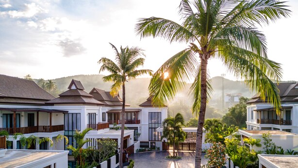 Un resort con varias villas, un patio central y palmeras.