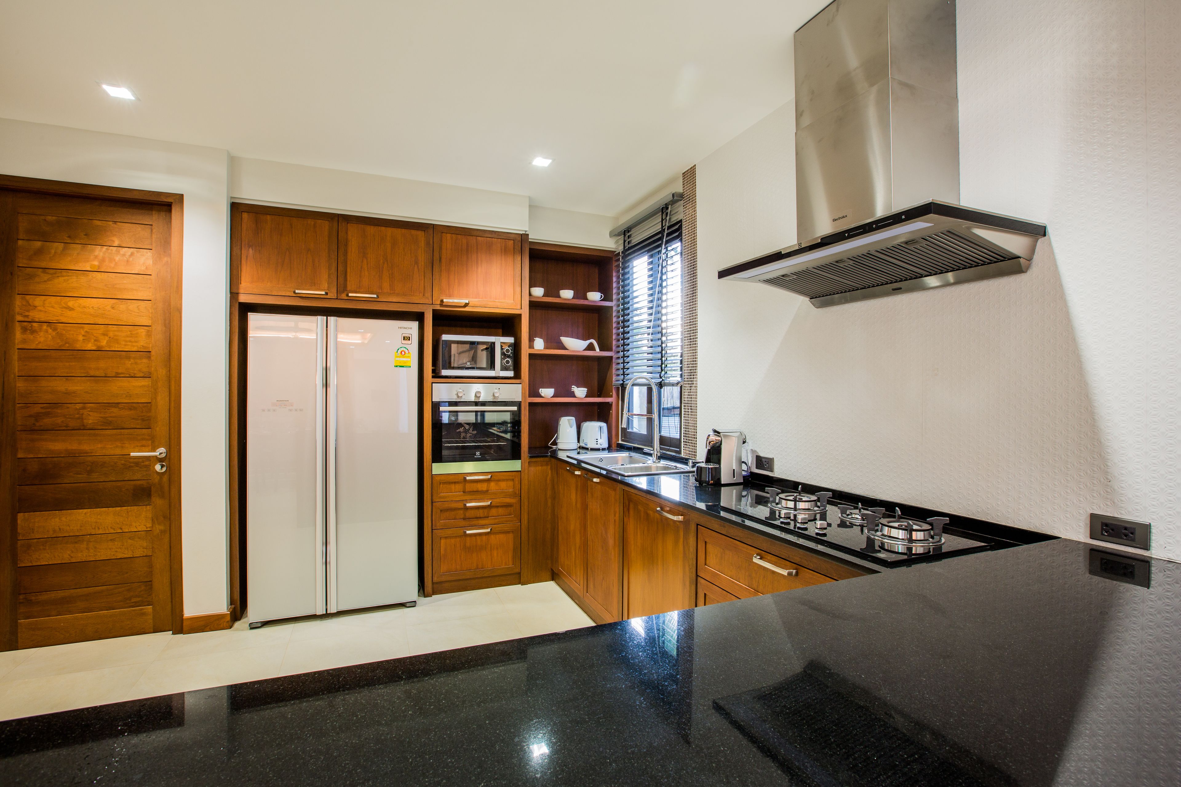 Una cocina moderna con armarios de madera, un microondas integrado y una campana extractora de acero inoxidable.