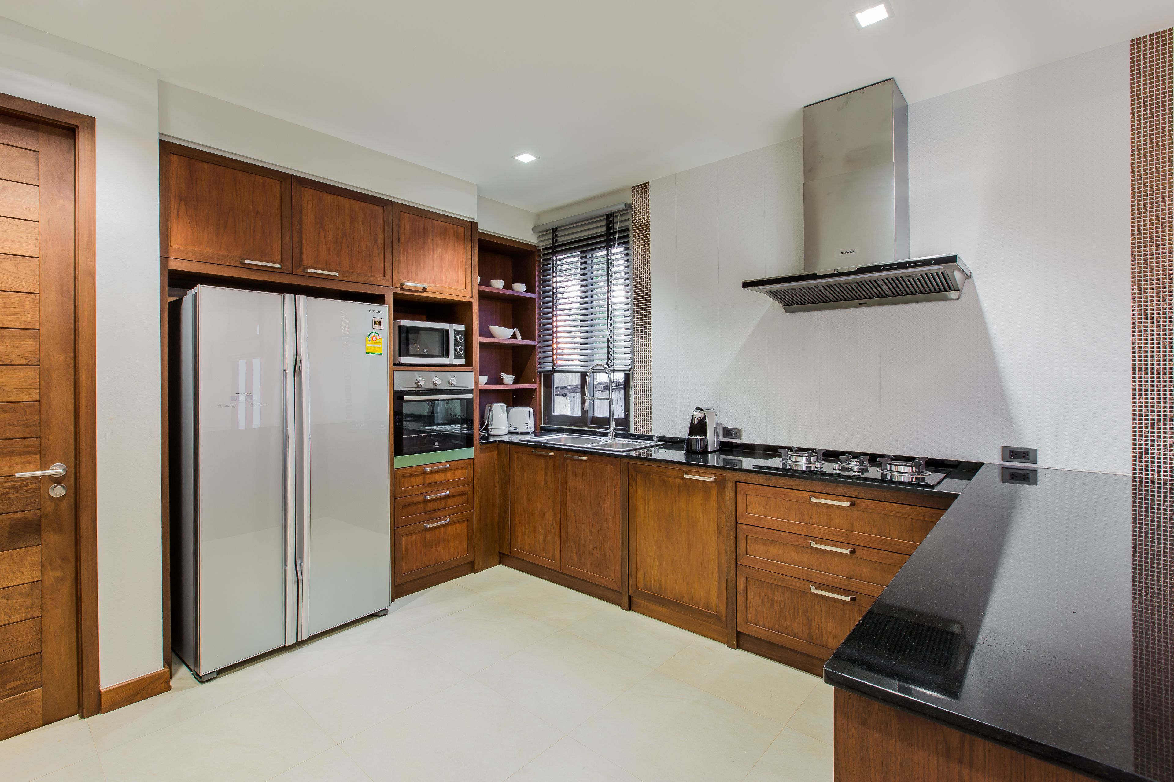 A modern kitchen with wooden cabinets, a stainless steel refrigerator, a microwave, and a gas stove.
