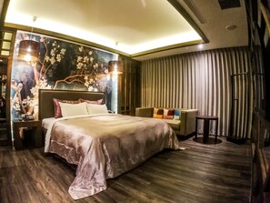 A modern hotel room with a large bed, a sofa, a small table, and a decorative wall mural. - SongXiaMotel (Taichung)