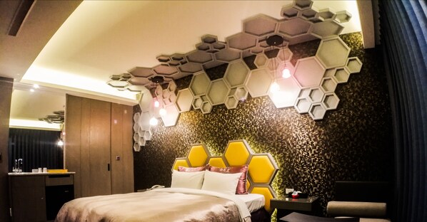 A modern hotel room with a unique hexagonal ceiling design, a bed with a yellow headboard, and a small bedside table. - SongXiaMotel (Taichung)