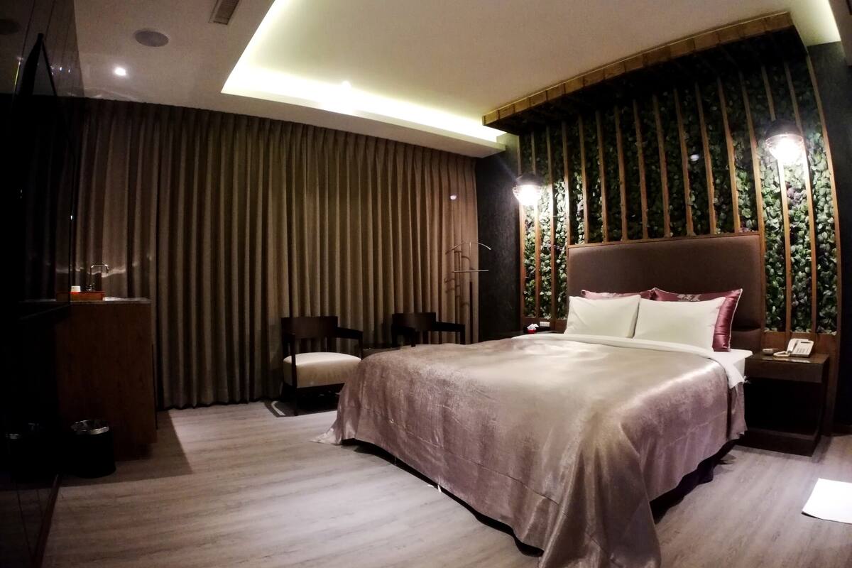 A modern hotel room with a large bed, a desk, and a chair.