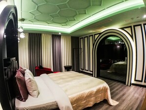 A hotel room with a large bed, a red chair, a small table, and a mirror. - SongXiaMotel (Taichung)
