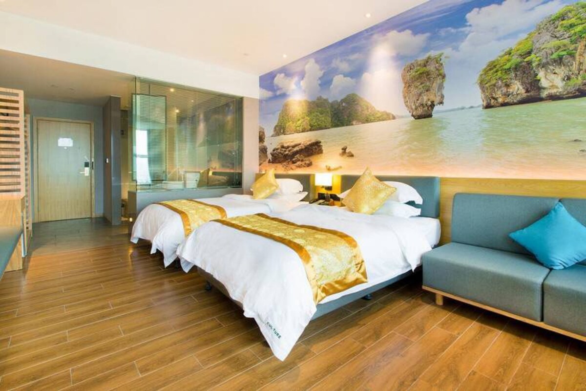 Ein Hotelzimmer mit zwei Betten, einer Sitzecke und einem großen Fenster mit Blick aufs Meer.