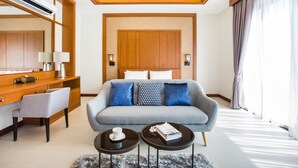 A modern hotel room with a sofa, two side tables, a desk with a chair, a large mirror, and a wooden headboard. - Villa Palavee B3 (Krabi)