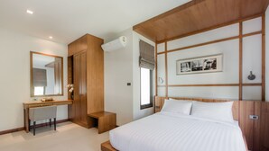 A modern bedroom with a wooden headboard, a large bed, a bedside table, a desk, and a mirror. - Villa Palavee B3 (Krabi)