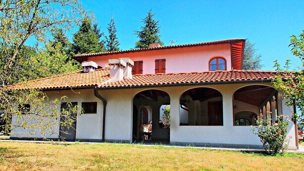 A two-story house with a red-tiled roof, white walls, and arched windows. - Villa Cristina (Vicchio)