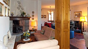 A cozy living room with a fireplace, a sofa, a coffee table with flowers, and a television in the background. - Villa Cristina (Vicchio)