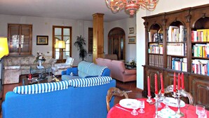 A living room with a blue sofa, a wooden bookshelf, and a chandelier. - Villa Cristina (Vicchio)