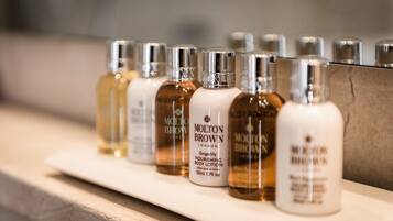A row of Molton Brown body lotion bottles on a shelf.